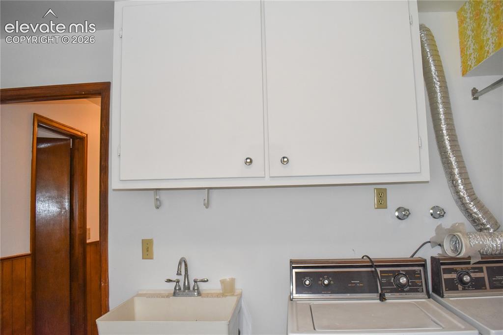 Image 33 of 44: White upper cabinetry, utility sink with chrome faucet, power outlets, and