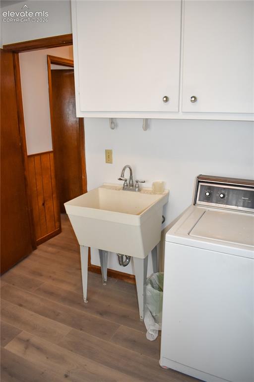 Image 34 of 44: Wood-finish flooring, white wall-mounted cabinetry, utility sink with chrom