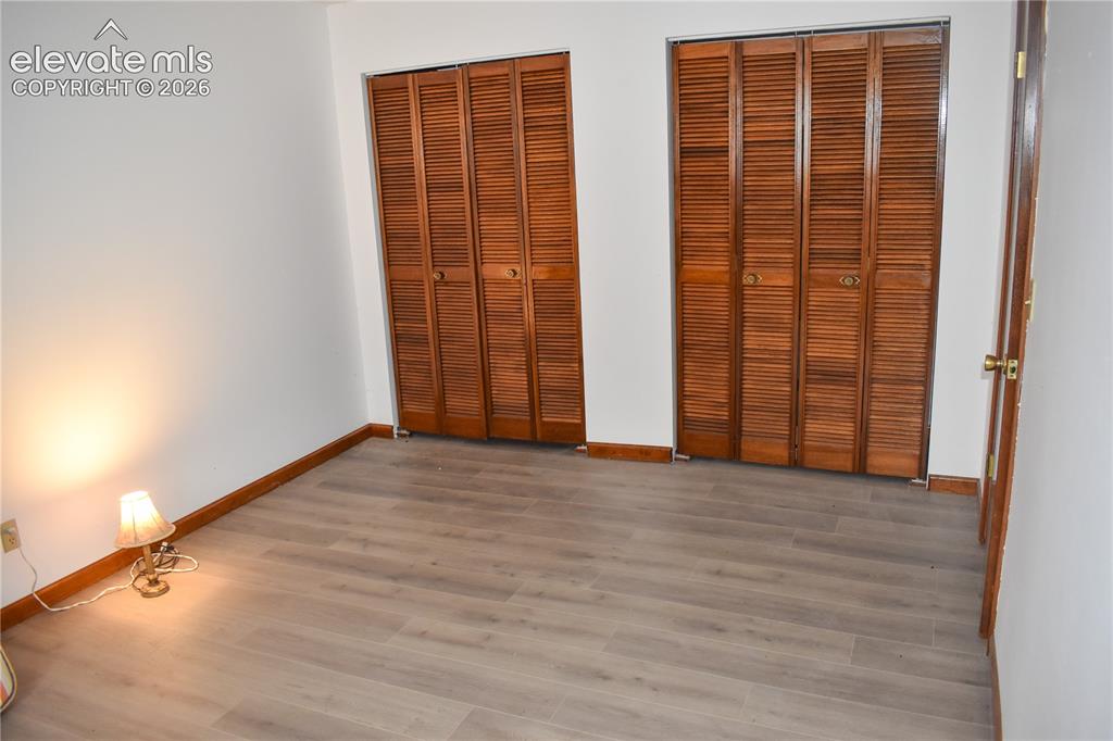 Image 36 of 44: Two sets of bi-fold louvered closet doors, wood-finish flooring, and white
