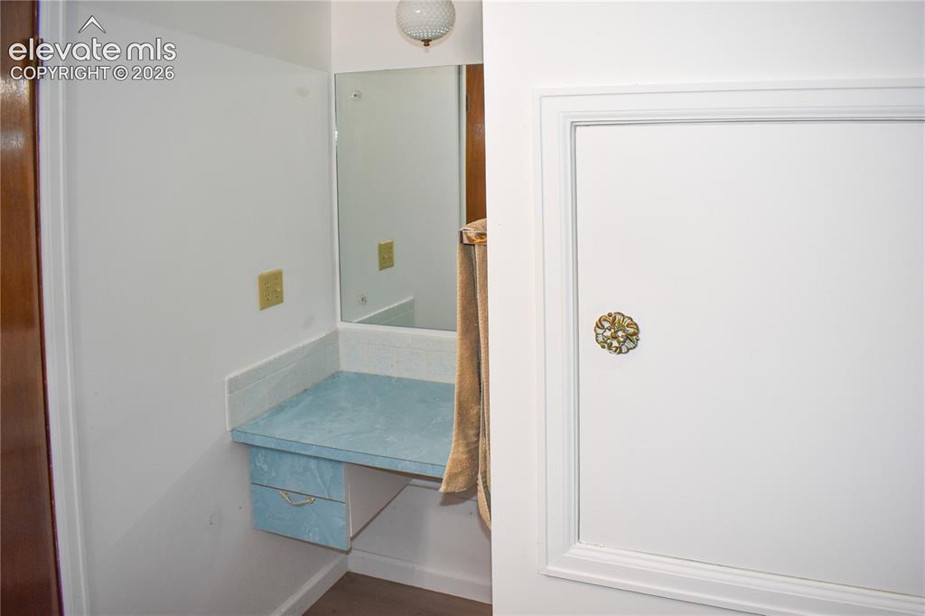 Image 39 of 44: Vanity area featuring a wall-mounted mirror, built-in countertop, and integ