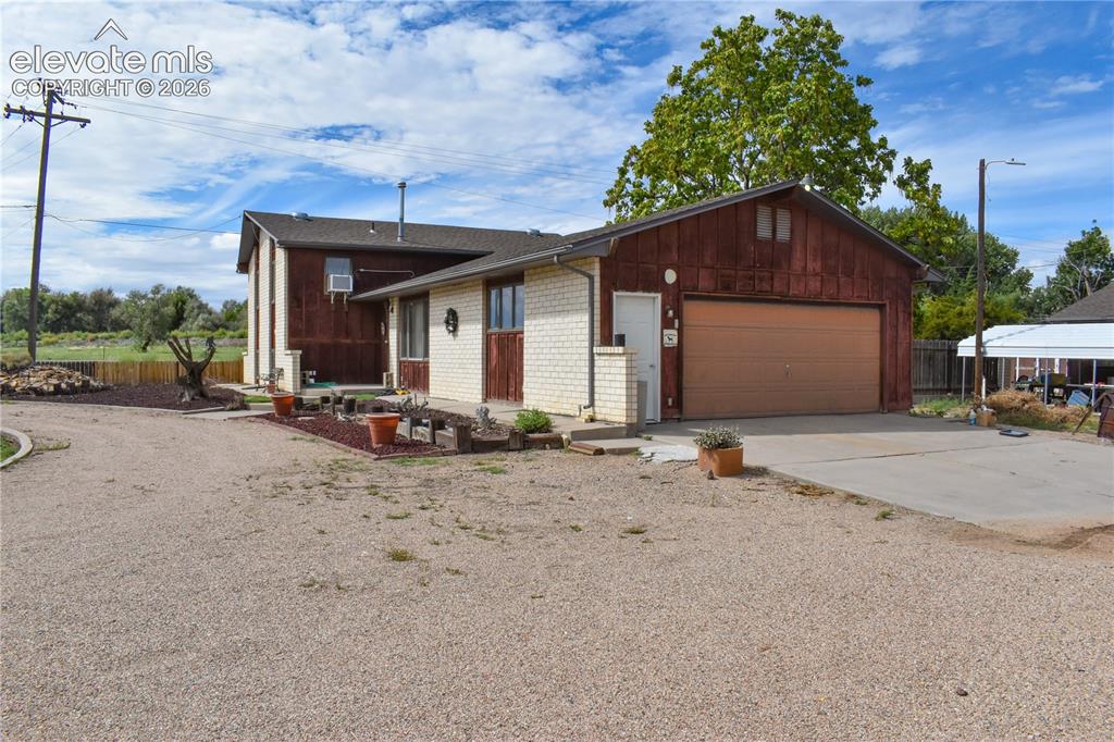 Image 4 of 44: Gravel driveway, attached garage with light-colored door, white brick facad