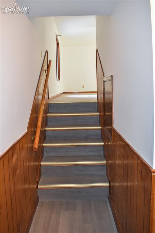 Image 41 of 44: Staircase featuring wood-finish treads with brass accents, wood paneling, a
