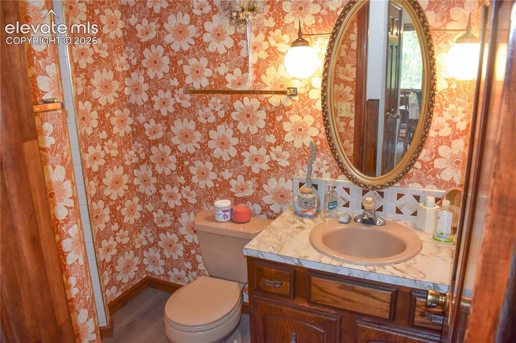 Image 42 of 44: Vanity with an oval mirror, dual wall-mounted light fixtures, and a culture