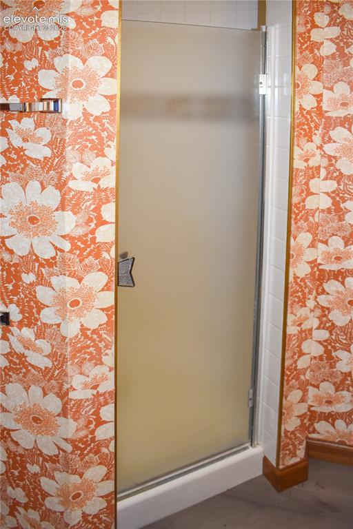 Image 43 of 44: Enclosed shower with frosted glass door, white tile surround, and gold-fini