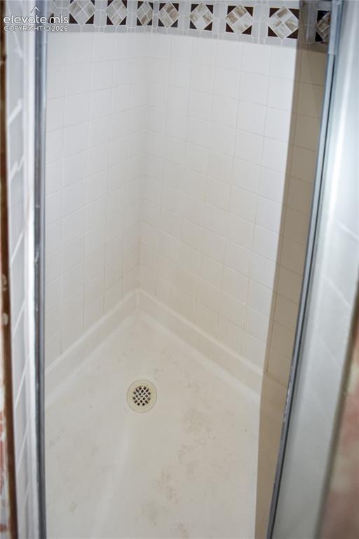 Image 44 of 44: White tile shower with mosaic accent border