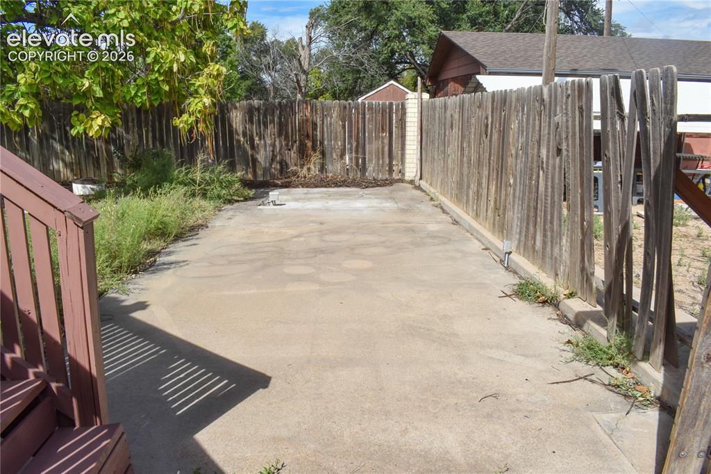 Image 5 of 44: Concrete patio area with wood fencing