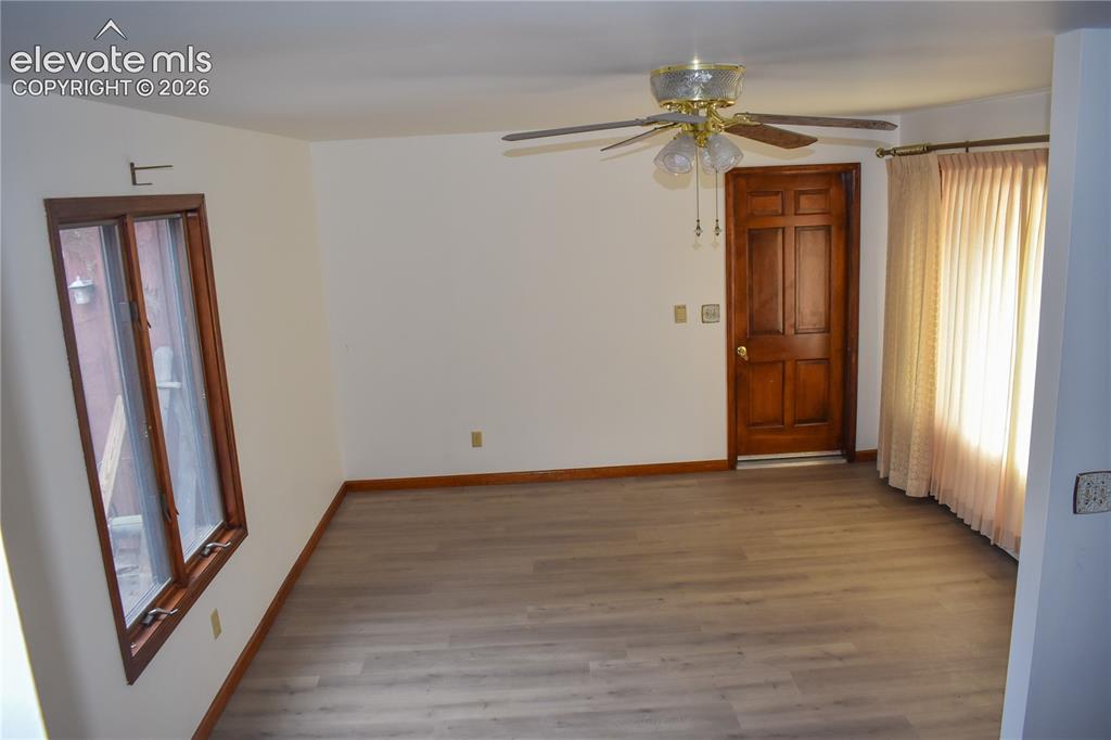 Image 9 of 44: Light wood-finish flooring, wood trim, white walls, and a ceiling fan with