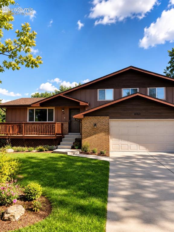 Image 1 of 1: Split-level residence featuring a two-car garage, expansive front lawn, and