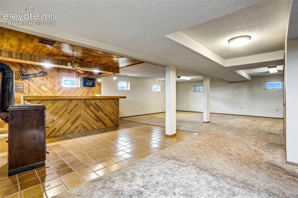 Image 30 of 48: wet bar, wood buring ceramic stove (can heat entire home), family room area