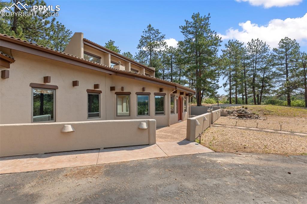 Image 17 of 50: View of side of home featuring stucco siding, a tile roof, and a patio area