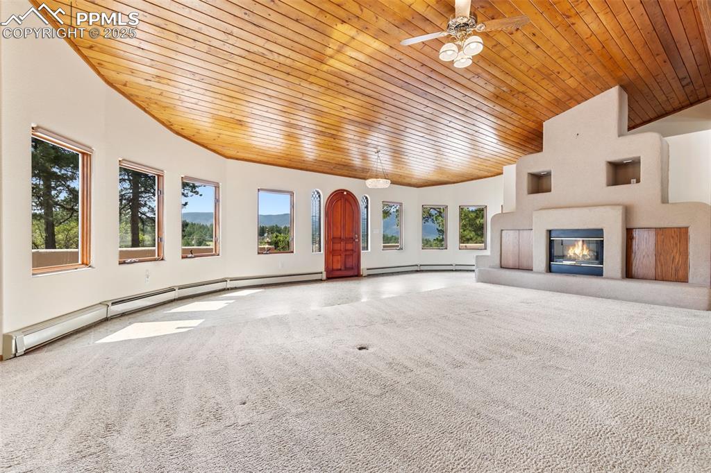 Image 18 of 50: Unfurnished living room with wood ceiling, a baseboard radiator, a glass co