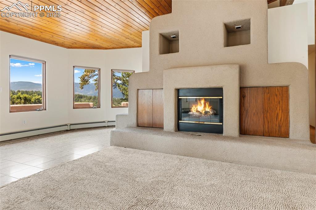 Image 19 of 50: Unfurnished living room featuring wood ceiling, a glass covered fireplace,
