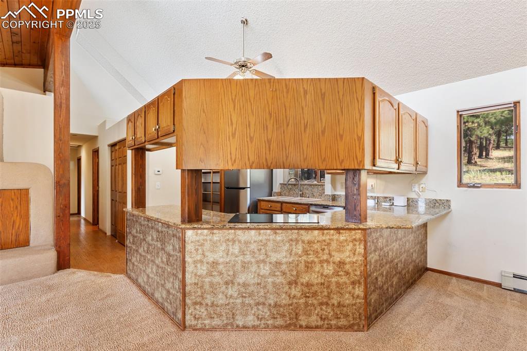 Image 24 of 50: Kitchen with light colored carpet, ceiling fan, freestanding refrigerator,