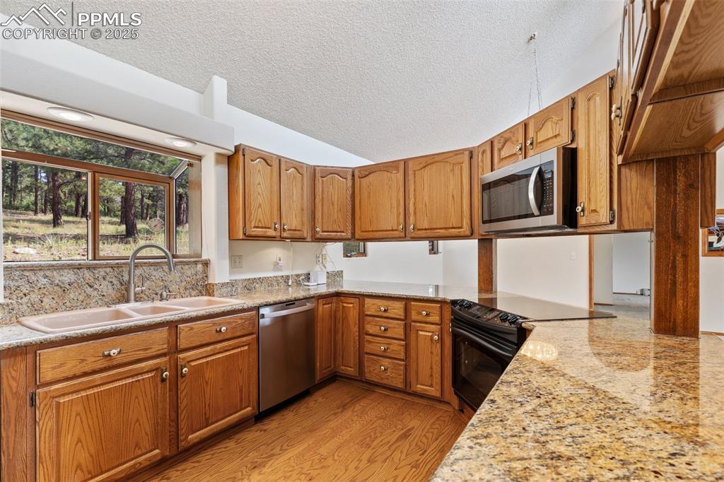 Image 25 of 50: Kitchen featuring light wood-type flooring, brown cabinetry, stainless stee