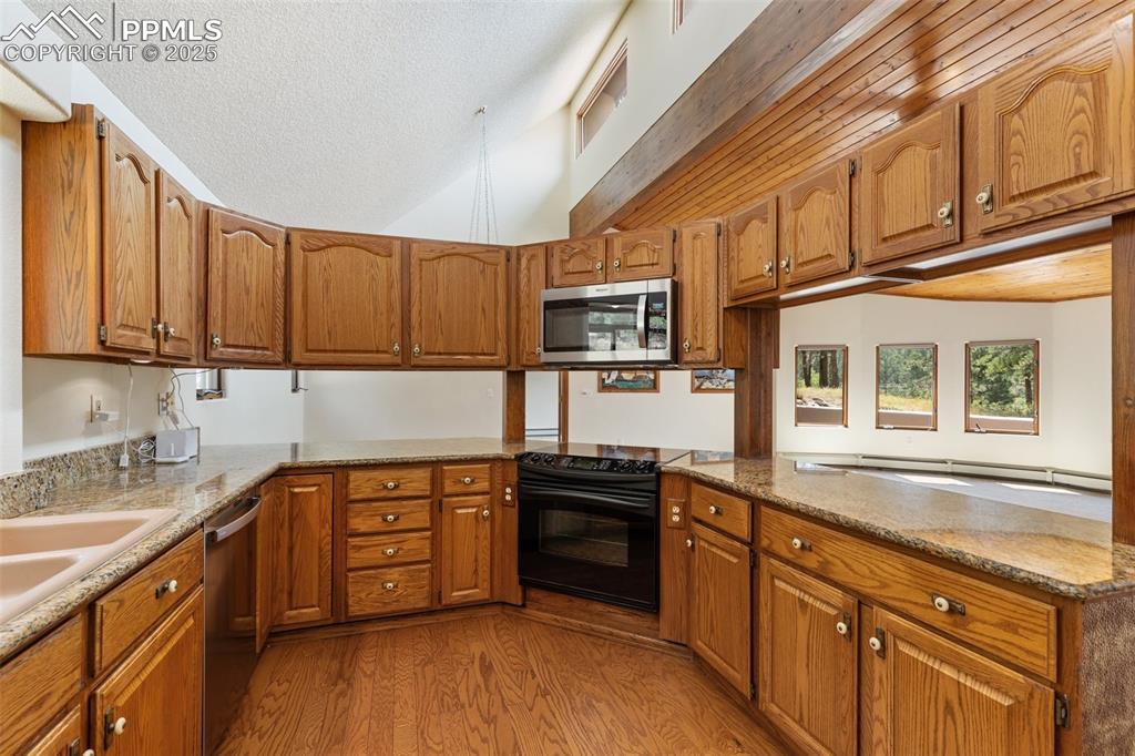 Image 27 of 50: Kitchen with brown cabinets, appliances with stainless steel finishes, ligh