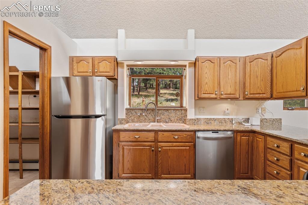 Image 30 of 50: Kitchen with appliances with stainless steel finishes, a textured ceiling,