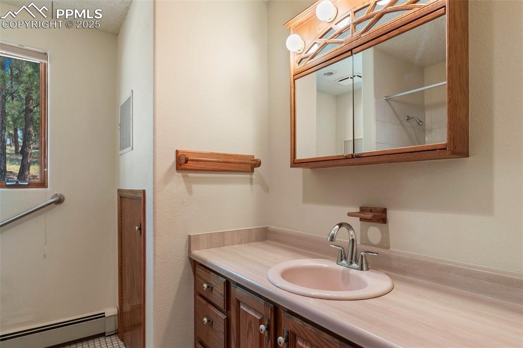 Image 31 of 50: Bathroom with a baseboard heating unit, vanity, a textured ceiling, and a s