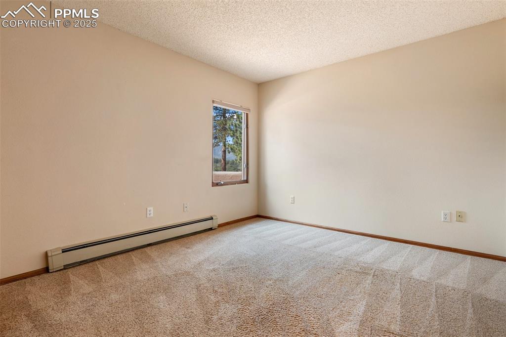 Image 33 of 50: Carpeted spare room featuring a baseboard radiator and a textured ceiling
