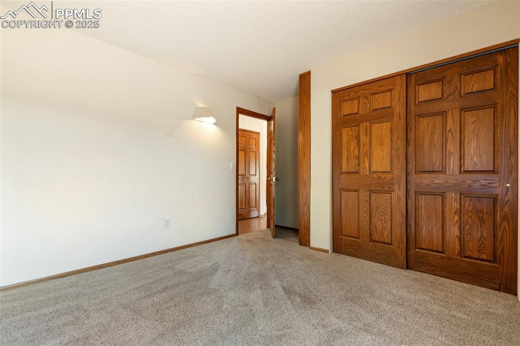Image 34 of 50: Unfurnished bedroom featuring carpet, a textured ceiling, and a closet