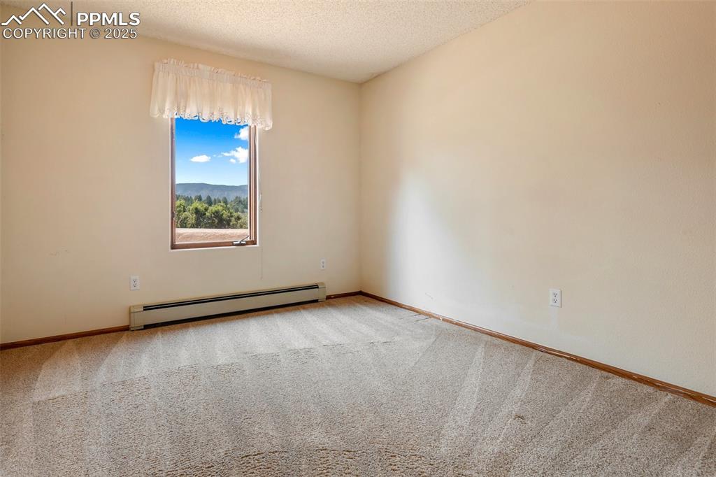 Image 35 of 50: Carpeted empty room featuring baseboard heating and a textured ceiling