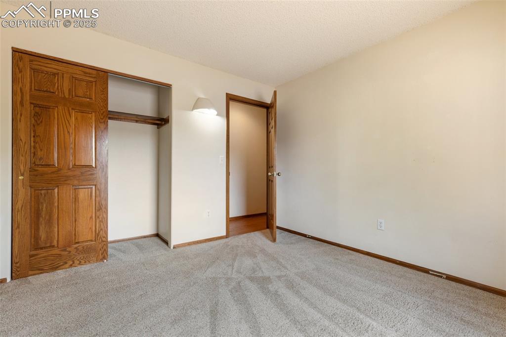 Image 36 of 50: Unfurnished bedroom with light colored carpet, a textured ceiling, and a cl