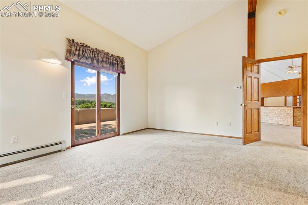 Image 38 of 50: Carpeted empty room featuring high vaulted ceiling, a mountain view, and ce