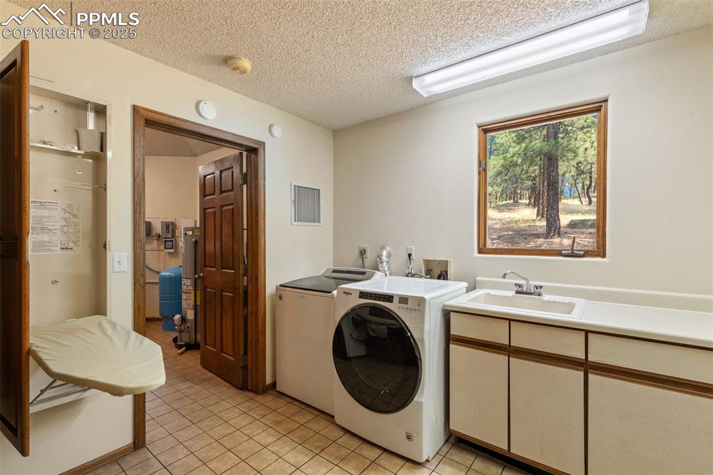 Image 46 of 50: Washroom featuring washing machine and clothes dryer, a textured ceiling, c