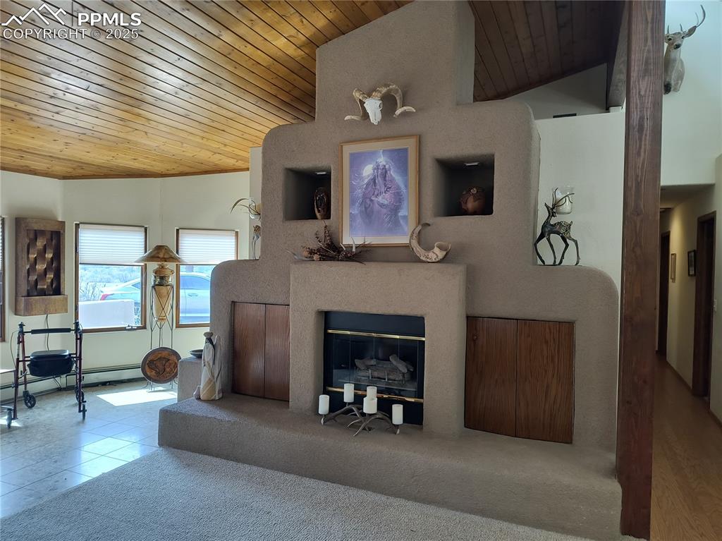 Image 6 of 50: Carpeted living room with wooden ceiling, vaulted ceiling, a glass covered