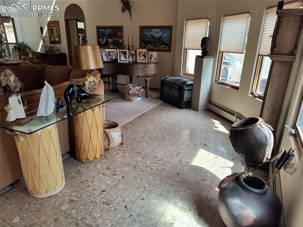 Image 8 of 50: Living room with a baseboard radiator, light flooring, and arched walkways