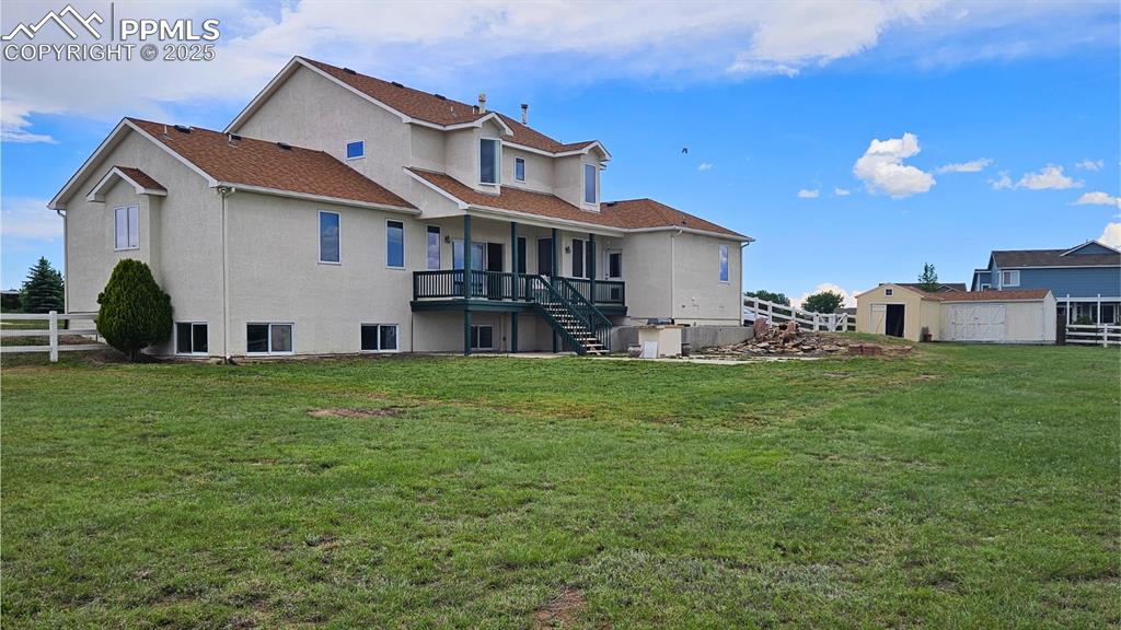 Image 3 of 28: Rear view of property featuring stairway to outdoor grill and fenced yard, 