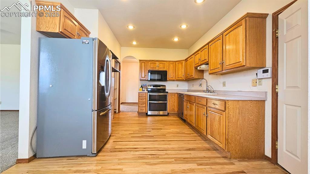 Image 4 of 28: Kitchen with stainless steel appliances, light wood-type flooring, light co