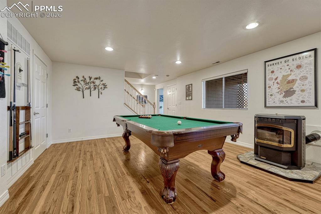 Image 31 of 49: Hardwood on Lower Level Rec Room and Pellet Stove