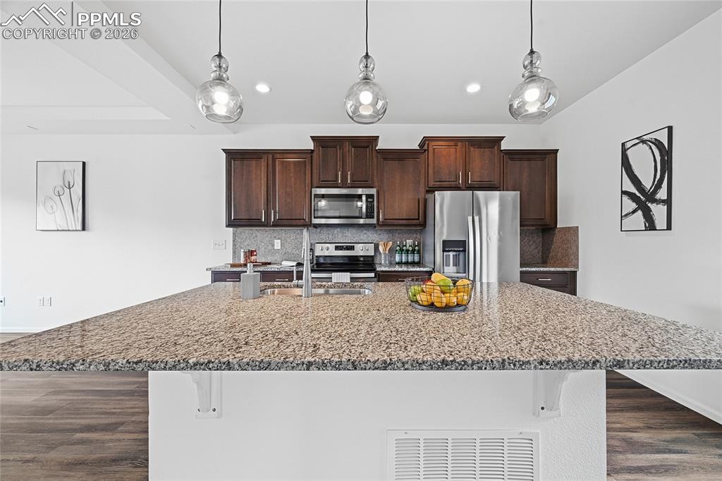Image 13 of 40: Kitchen with a breakfast bar area, dark wood finish cabinets, stainless ste