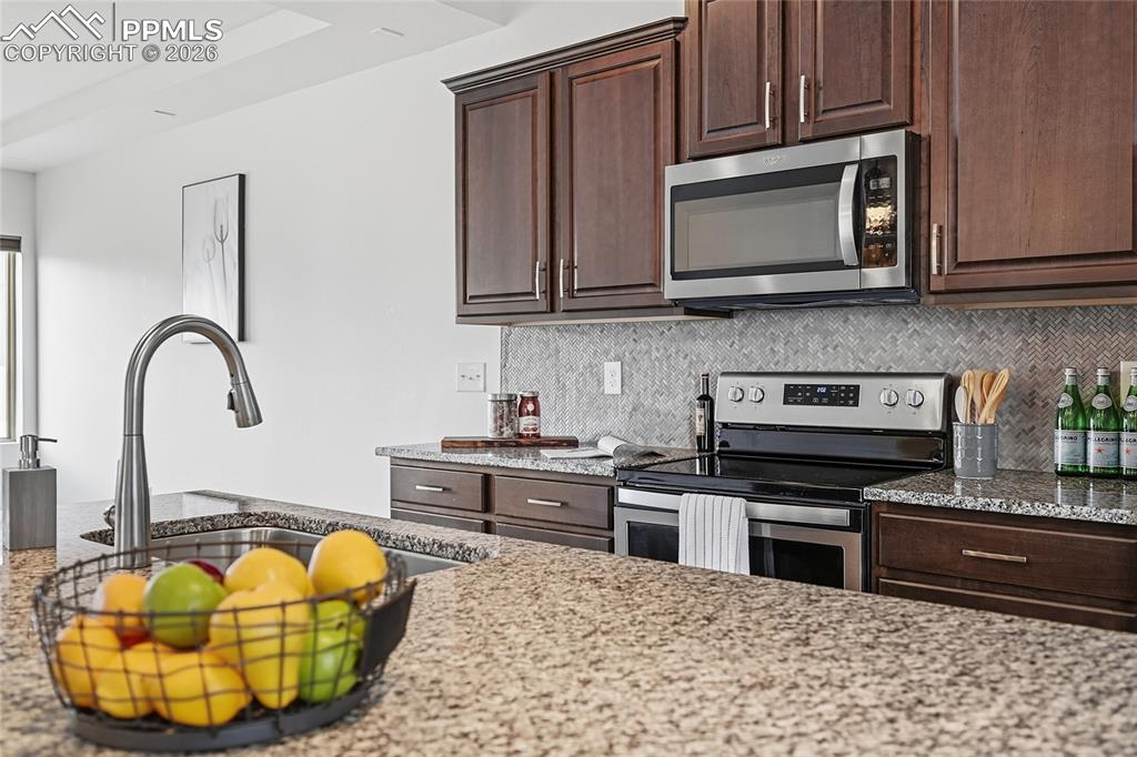 Image 15 of 40: Kitchen with stainless steel appliances, dark wood finish cabinetry, light 