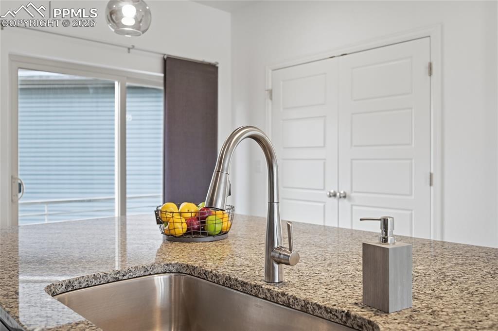 Image 16 of 40: Kitchen view of light stone countertops, a stanless steal sink, pantry room