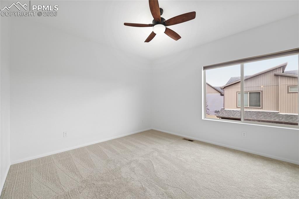 Image 17 of 40: Unfurnished primary bedroom with light carpet and a ceiling fan
