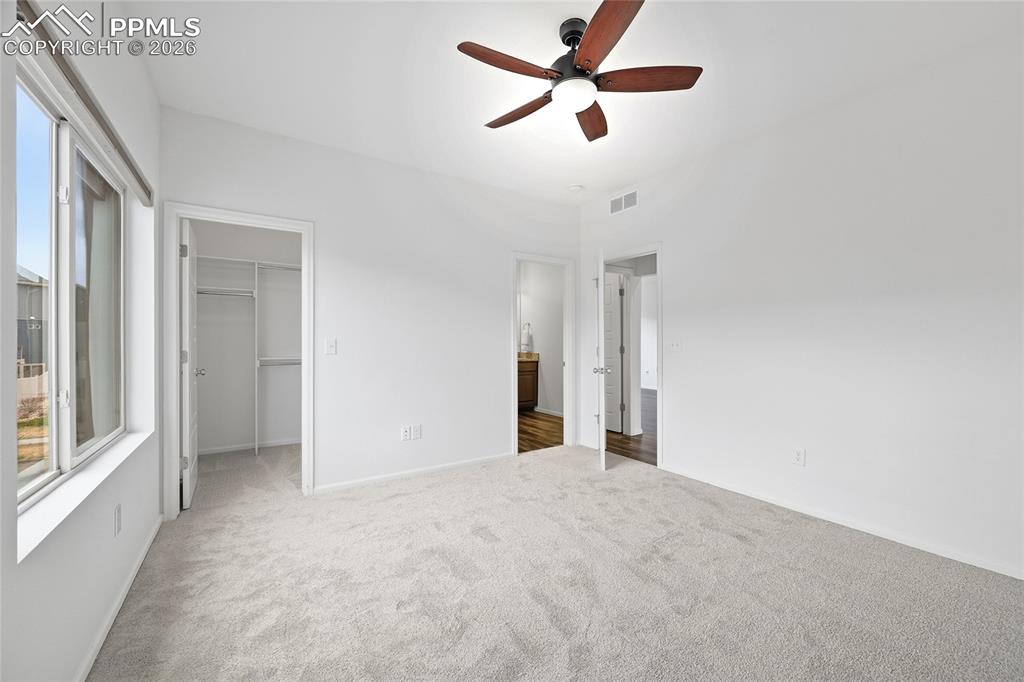 Image 18 of 40: Unfurnished primary bedroom with light carpet floors, a walk in closet, a c