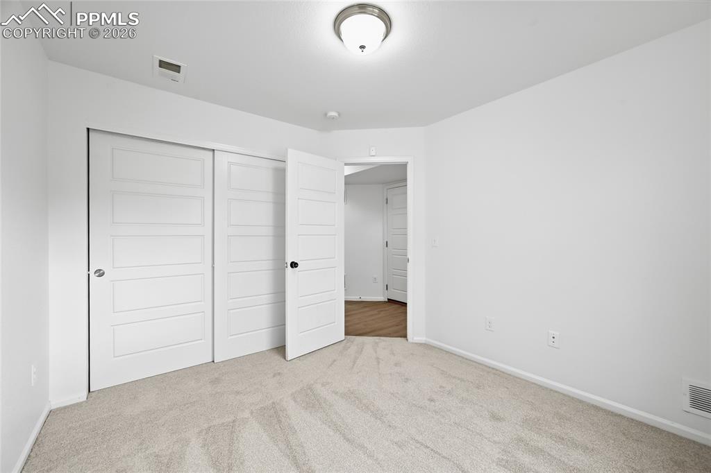 Image 24 of 40: Unfurnished secondary lower-level bedroom featuring light carpet and a clos