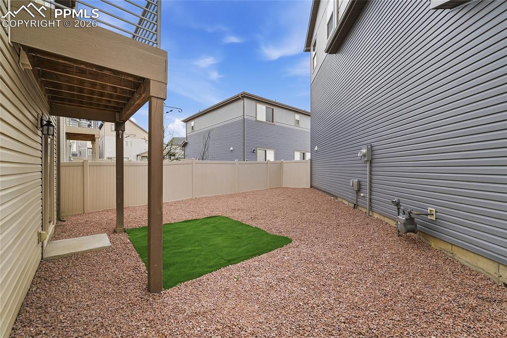 Image 29 of 40: Fenced backyard featuring a patio area with rocks and turf