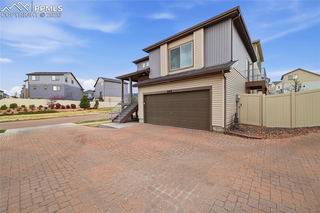 Image 3 of 40: View of front of house with a garage, decorative driveway, and a residentia