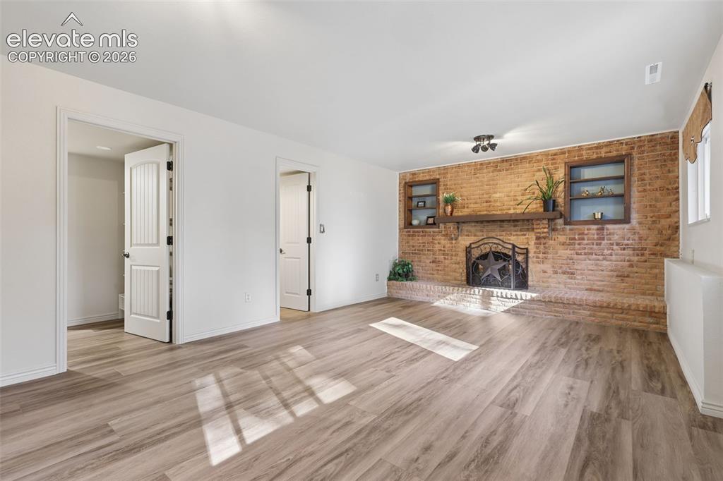 Image 17 of 32: Lower Level Family Room with brick wood burning fireplace