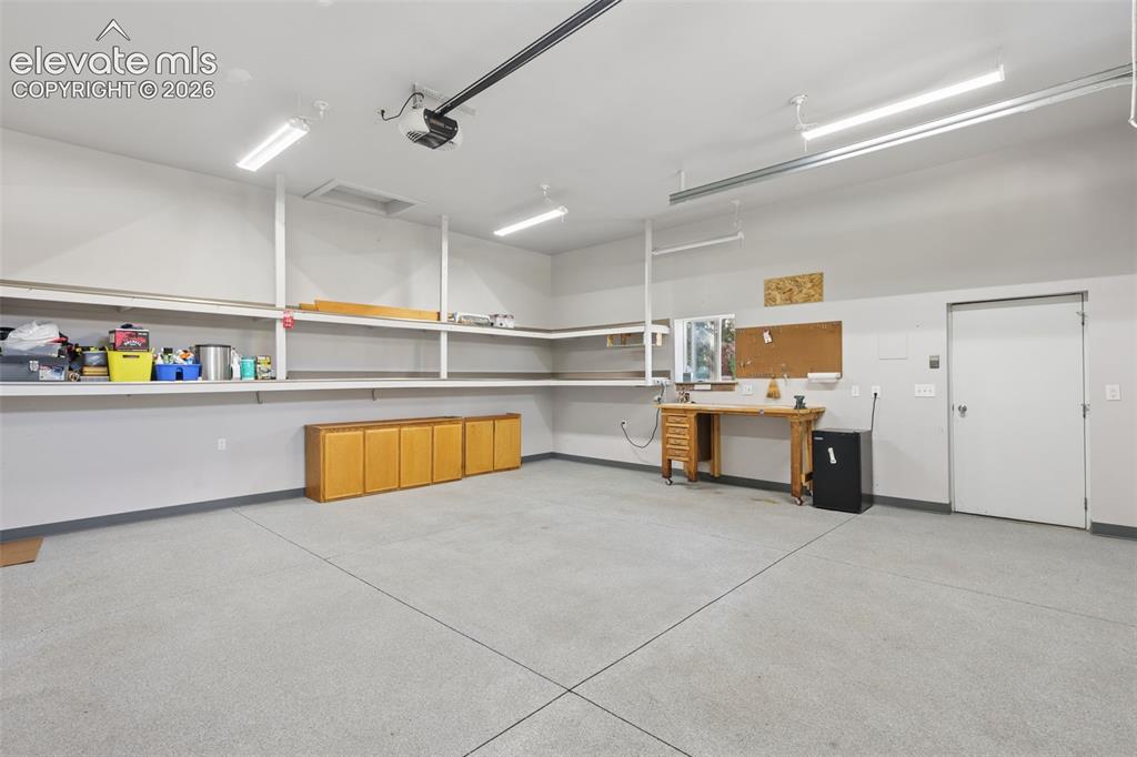 Image 31 of 32: Detached Garage Interior with BI shelves, drywall finish, epoxy floor, and