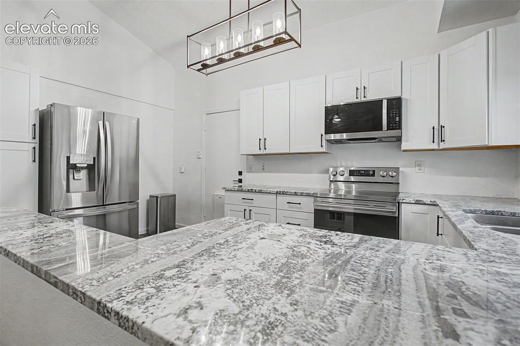 Image 11 of 37: Kitchen featuring light-toned countertops, white cabinetry with dark hardwa