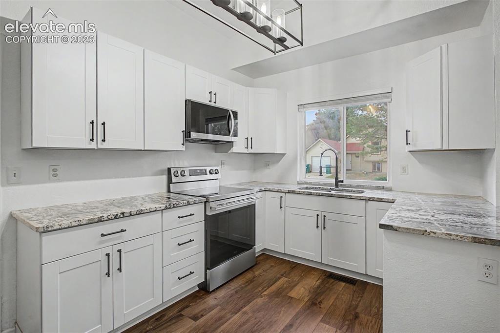 Image 13 of 37: Kitchen featuring white shaker-style cabinetry, patterned countertops, stai