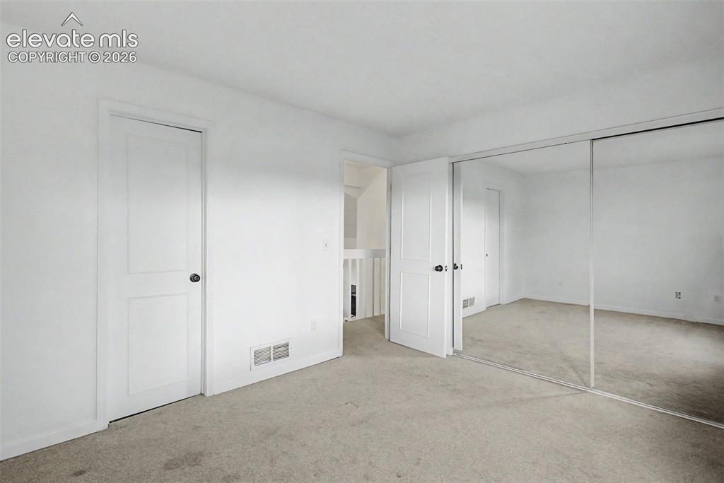 Image 18 of 37: Carpeted interior room featuring a mirrored sliding closet door, white pain