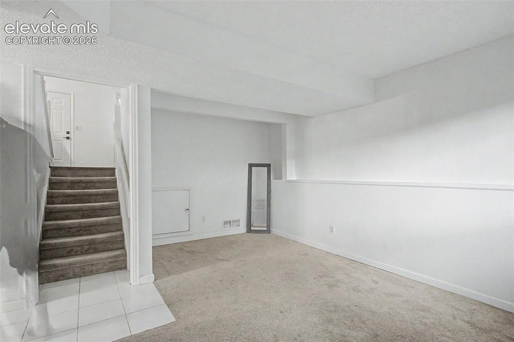 Image 23 of 37: Carpeted floor area with white walls and baseboards