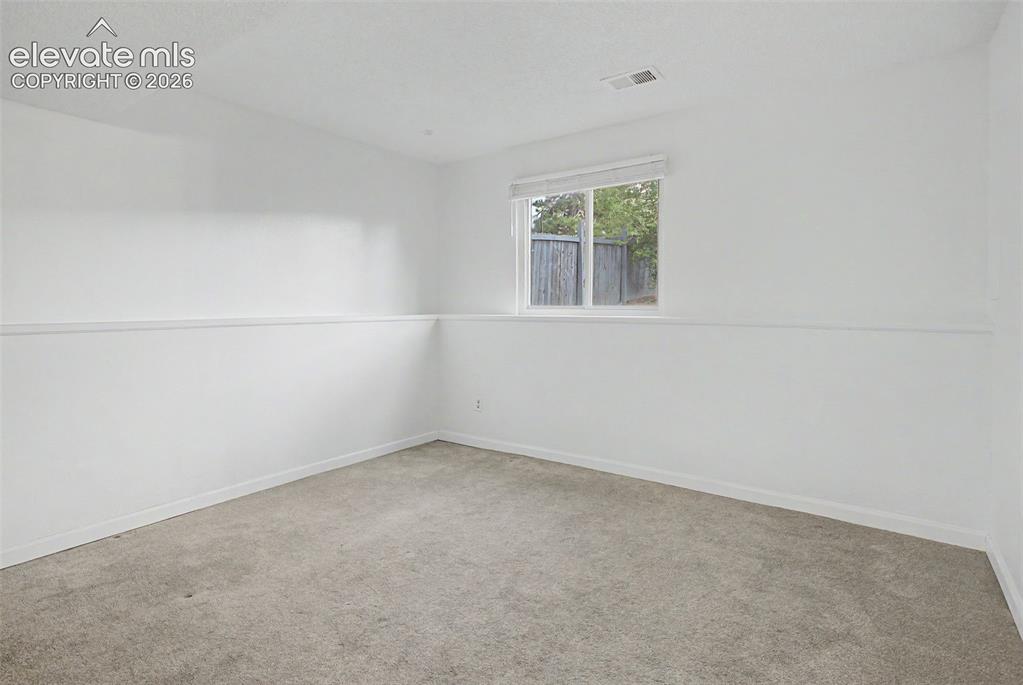 Image 24 of 37: Carpeted room with a single window and white walls