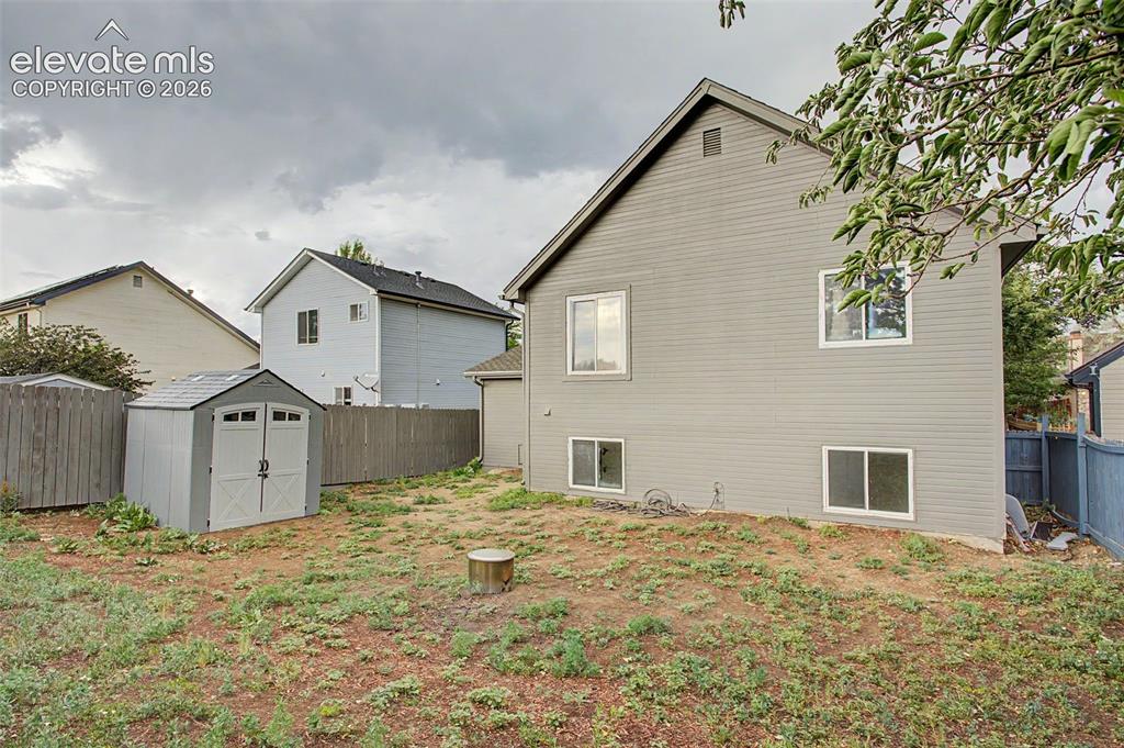 Image 28 of 37: Rear exterior featuring gray horizontal siding, multiple windows, and a pea