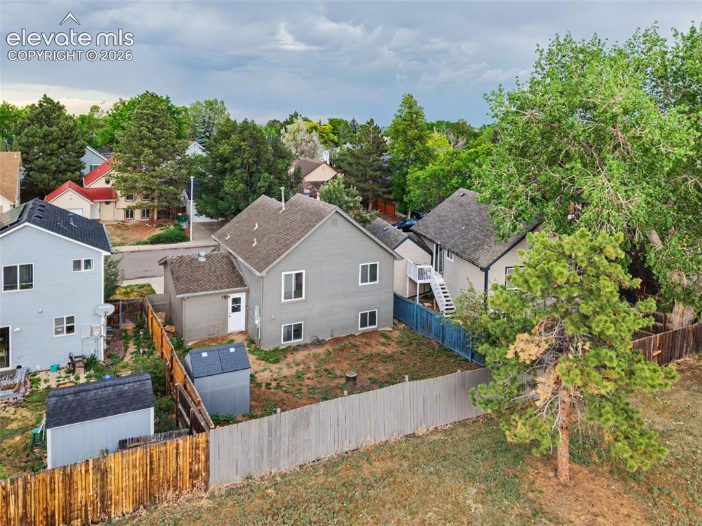 Image 32 of 37: Expansive fenced yard featuring two storage sheds, mature trees, and a grav