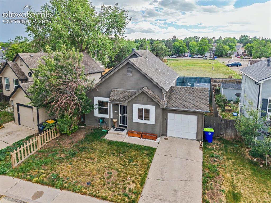 Image 35 of 37: Gray exterior residence featuring a front yard, attached garage, and paved